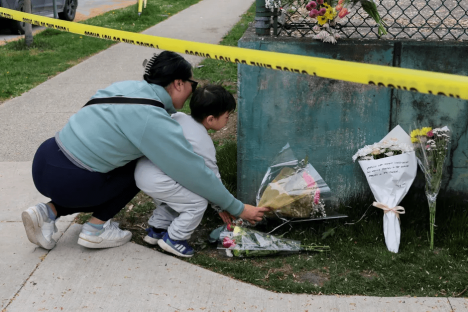 A woman and child placing flowers at a memorial.