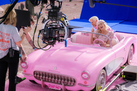 Margot Robbie and Ryan Gosling filming a scene in a pink car for the Barbie movie.