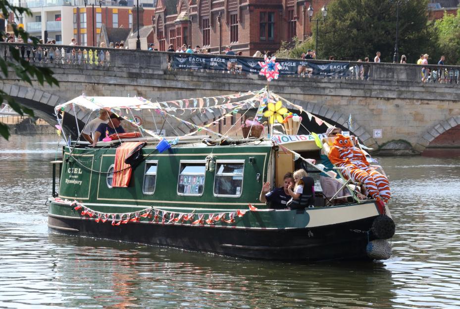 A decorated boat with people on it at the Bedford River Festival.
