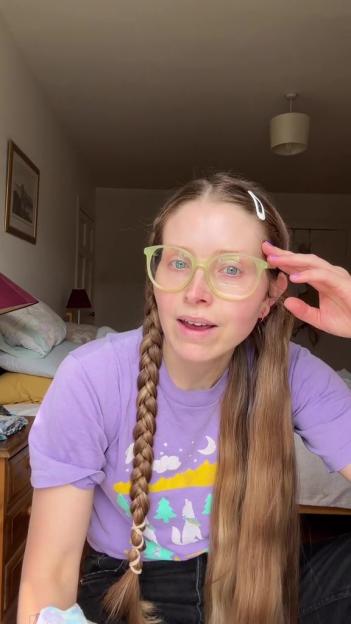 Jessie Cave in a purple T-shirt with braids and glasses.