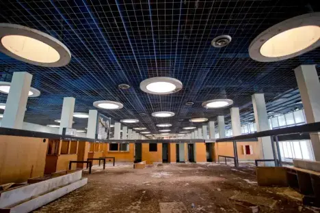 Interior of an abandoned building with a gridded ceiling and round lights.