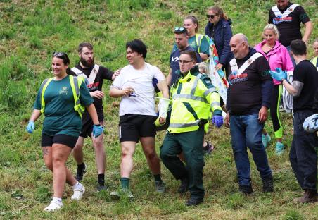 A cheese-rolling contestant being assisted by medical personnel after a race.