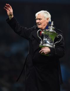 Peter McParland, former Aston Villa player, holding the FA Cup and waving.