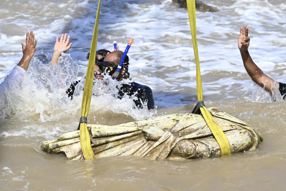 Divers recovering an artifact from the water.