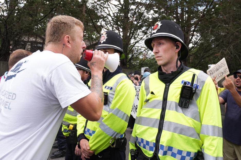 Protestor using a megaphone speaks to police officers during a demonstration.