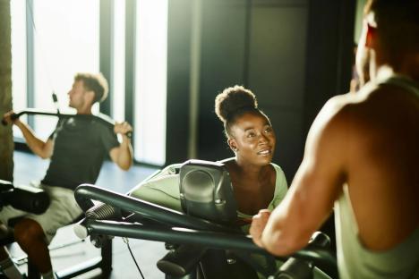 Woman talking to a man in a gym.
