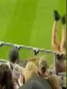 A person falling from a stadium seating area onto the field below.