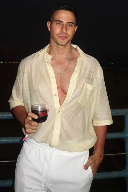 Man in a light yellow shirt holding a drink.