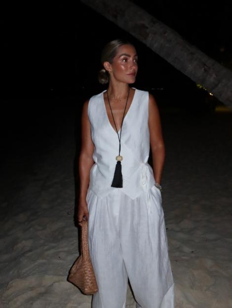 Rochelle Humes wearing a white linen vest and pants on a beach at night.