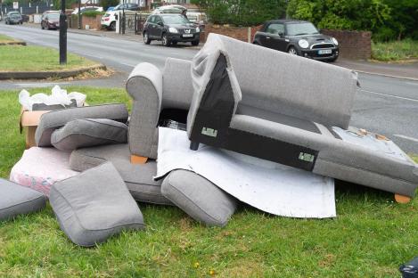 Fly-tipped furniture and rubbish on a residential street.