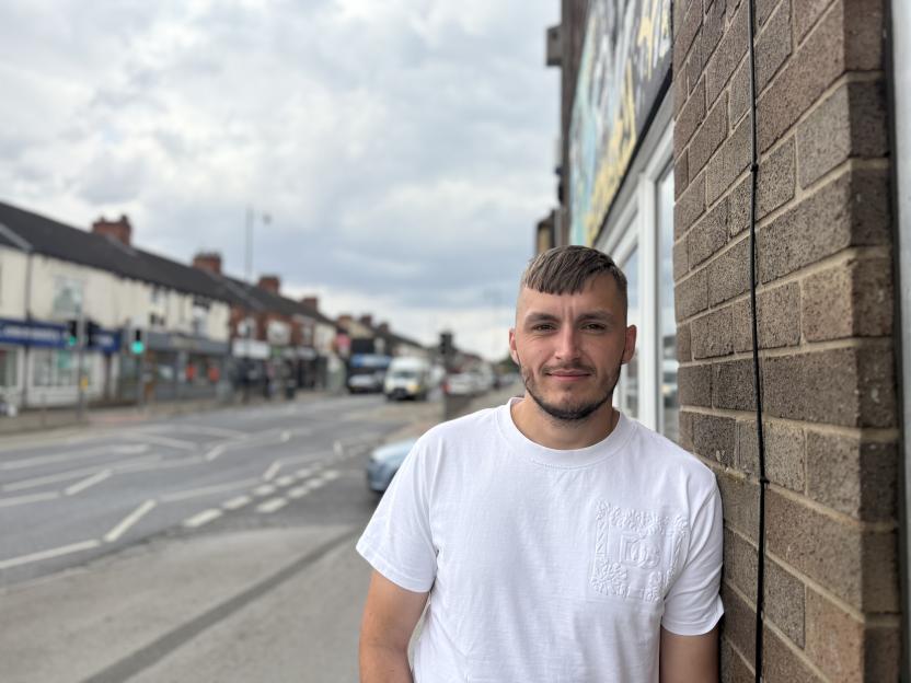 Tom Kirk, a recovering ketamine addict, stands beside a brick wall.