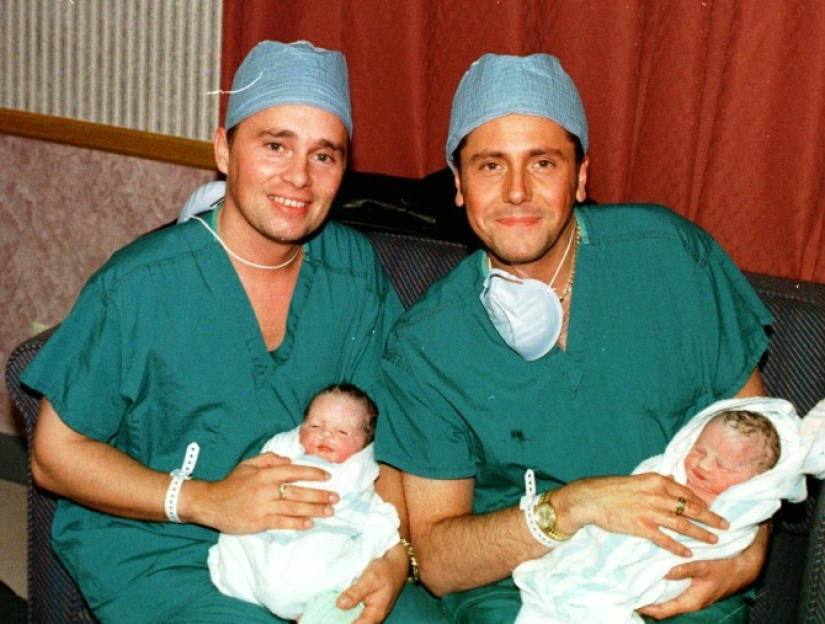 two men in scrubs are holding two newborn babies
