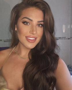 Woman with long brown hair and gold necklace.