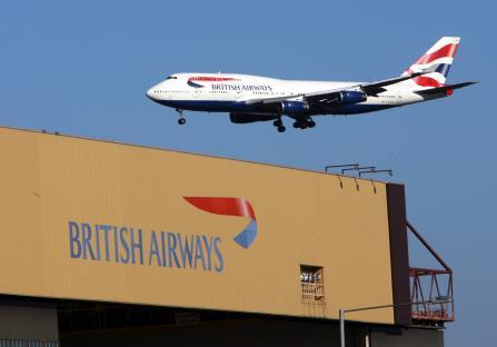 British Airways jet flying over a British Airways building.