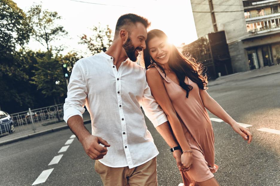 Happy young couple holding hands and walking down a city street.