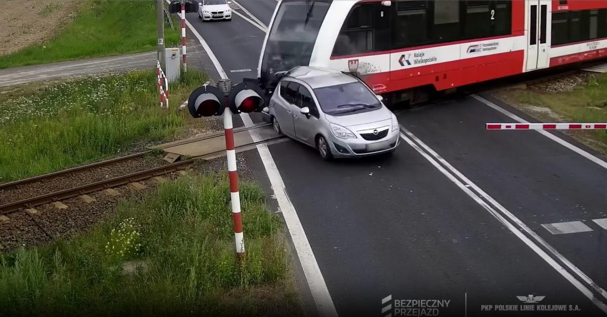 Car crashes through railway barrier and is hit by train.