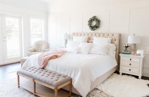 White bedroom with a tufted bed, bench, and nightstand.