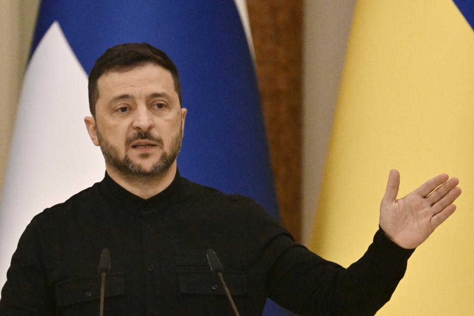 Ukrainian President Volodymyr Zelensky speaking at a press conference with his hand outstretched.