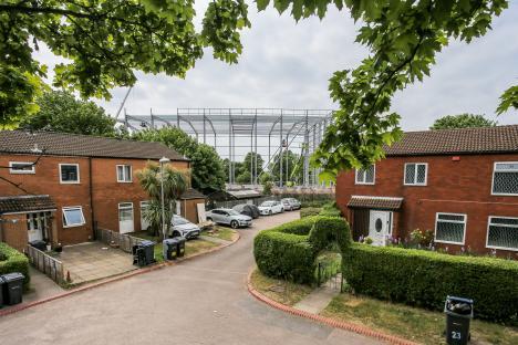 Large warehouse under construction looming over residential homes.