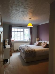Bedroom after renovation with mauve walls and a large bed.