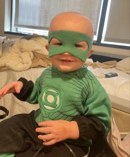Toddler in Green Lantern costume in hospital.