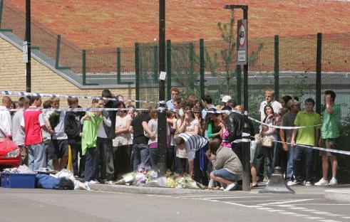Mourners lay flowers at a murder scene.