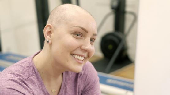 a woman with a shaved head is smiling in front of a treadmill
