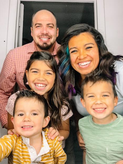 A smiling family of five, with two adults and three children.