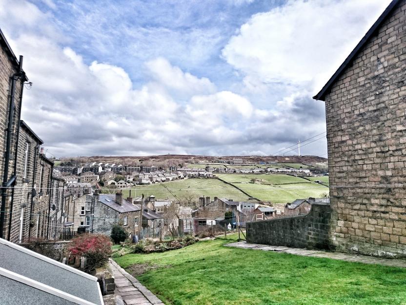 Terraced houses on a hillside with a wind turbine in the distance.