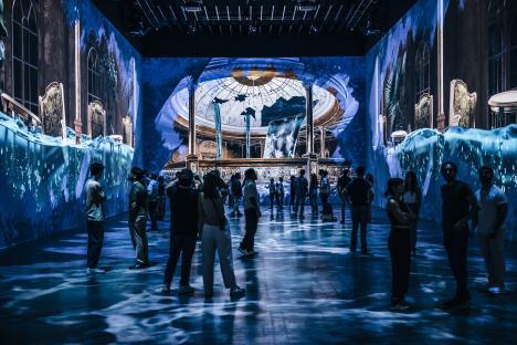People viewing a Titanic exhibition featuring immersive projections of the ship's interior.