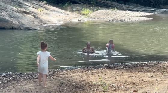 Woman and two children playing in a river.