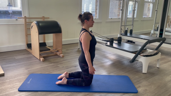 Woman performing a Pilates exercise on her knees.