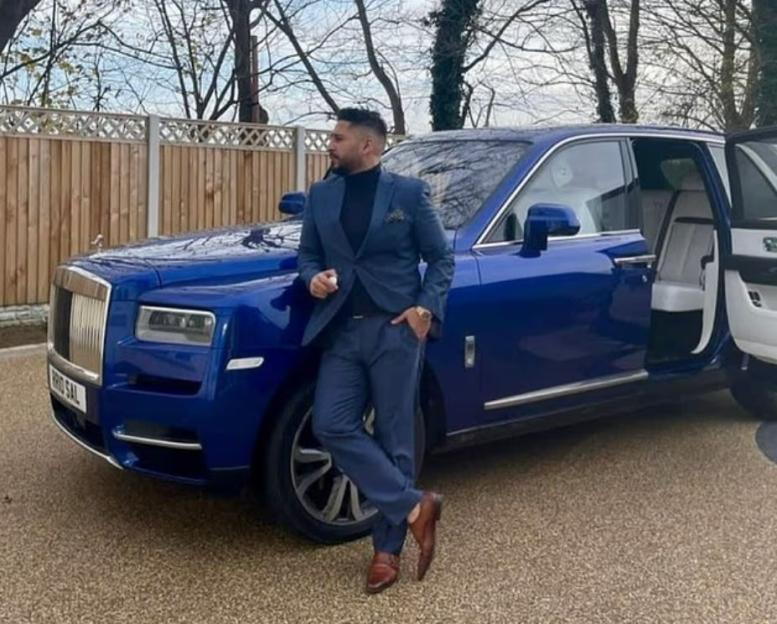 Salman Iftikhar standing next to a blue Rolls-Royce Cullinan.