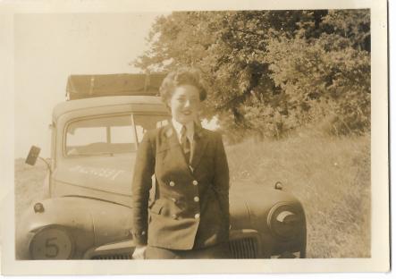 Woman in uniform standing in front of a vintage truck.