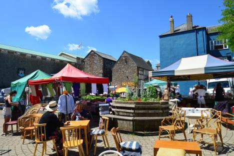 Market square in Totnes, England, with market stalls and people.