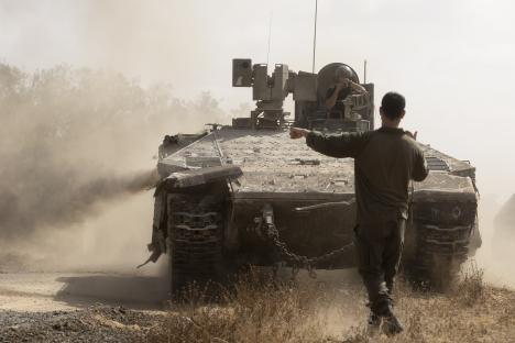 Israeli soldier directing an armored personnel carrier near the Gaza Strip border.