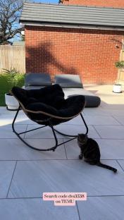 Black rocking chair on patio with cat.