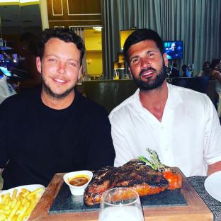 Two men sharing a large steak dinner.