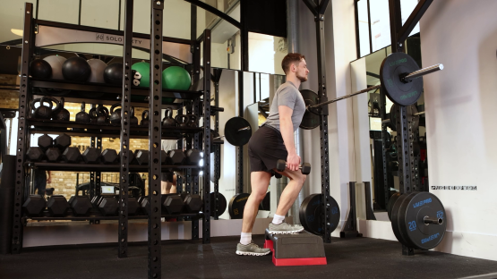 Man performing a dumbbell split squat in a gym.