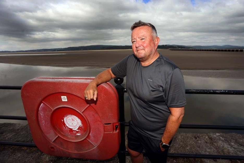 Man standing by a life ring on a pier.