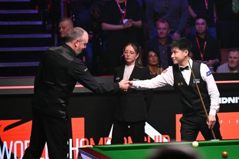 Mark Williams and Zhao Xintong shaking hands at the start of a snooker match.