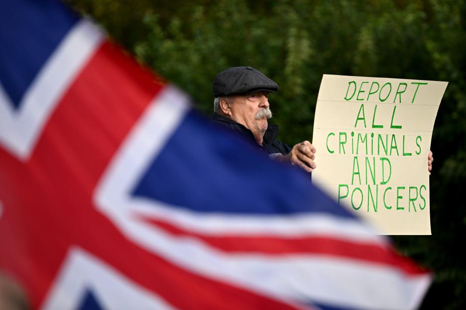Protestor holding a sign that reads "DEPORT ALL CRIMINALS AND PONCERS".