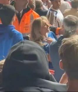 A woman being confronted by a man in a crowded stadium.