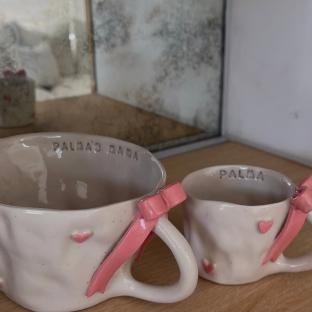 Two ceramic mugs with pink bows and hearts.