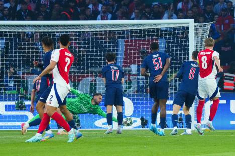 Martin Ãdegaard of Arsenal shoots at goal, with the PSG goalkeeper making a save.