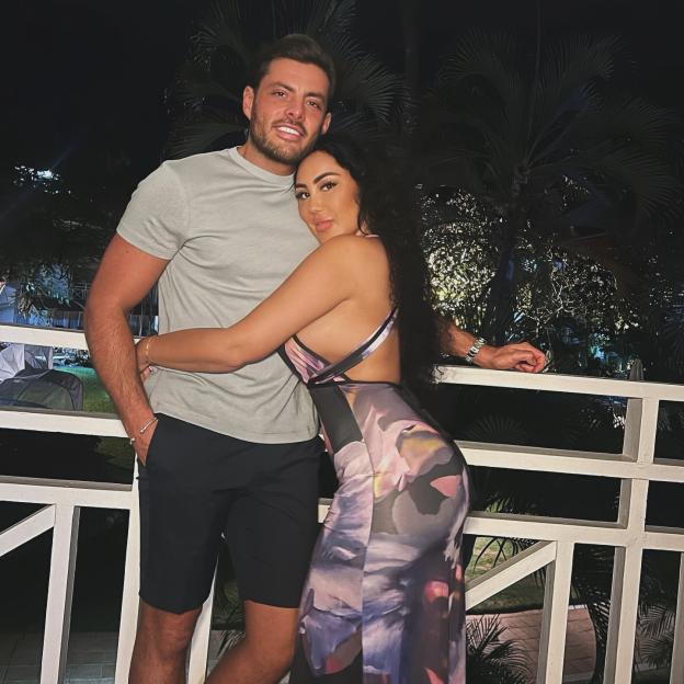 Jordan Brook and Sophie Kasaei embrace on a balcony at night.
