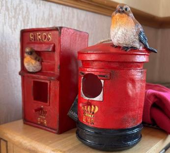 Two red birdhouses shaped like mailboxes, one with a robin perched on top.