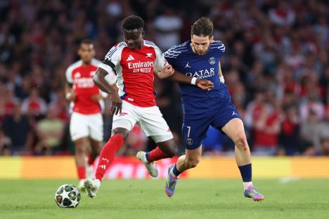 Bukayo Saka of Arsenal and Khvicha Kvaratskhelia of Paris Saint-Germain in action during a Champions League match.