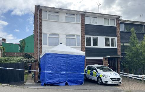 Crime scene at a house with a police car and tent.