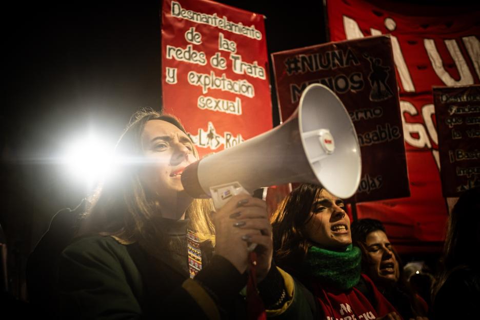 People protest against gender-based violence and femicide, with megaphones and banners.